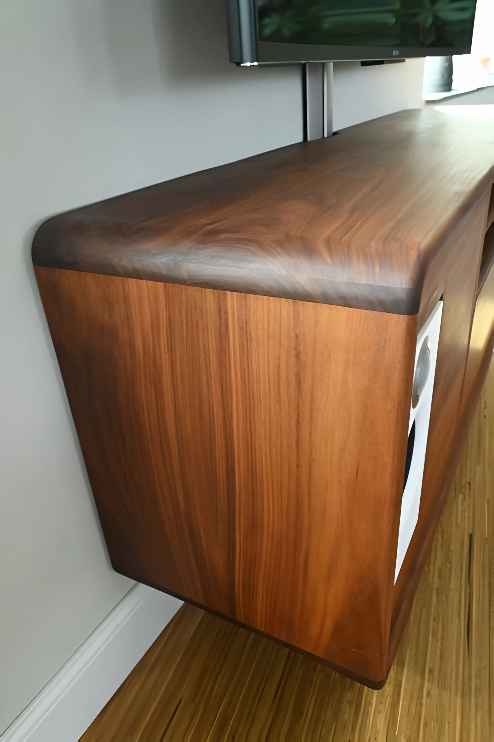 Linkerzijkant van tv-meubel met vloeiende ronding in massief walnoot | Ambachtelijke afwerking van maatwerk woonkamermeubel